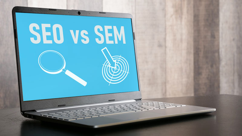 A laptop with graphics that say “SEO vs SEM”